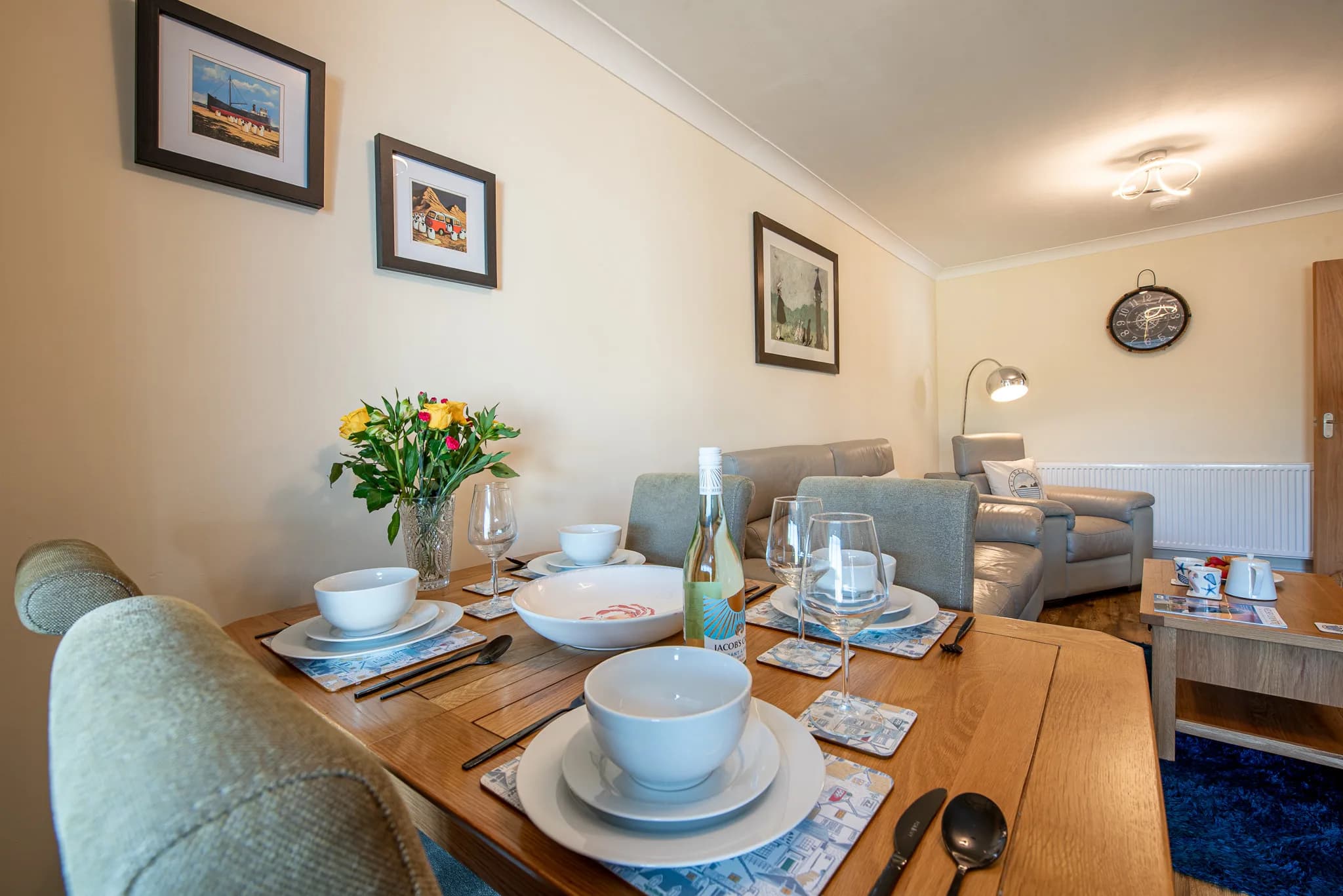 Dining table set for four, open to the living room at Sea Dreams